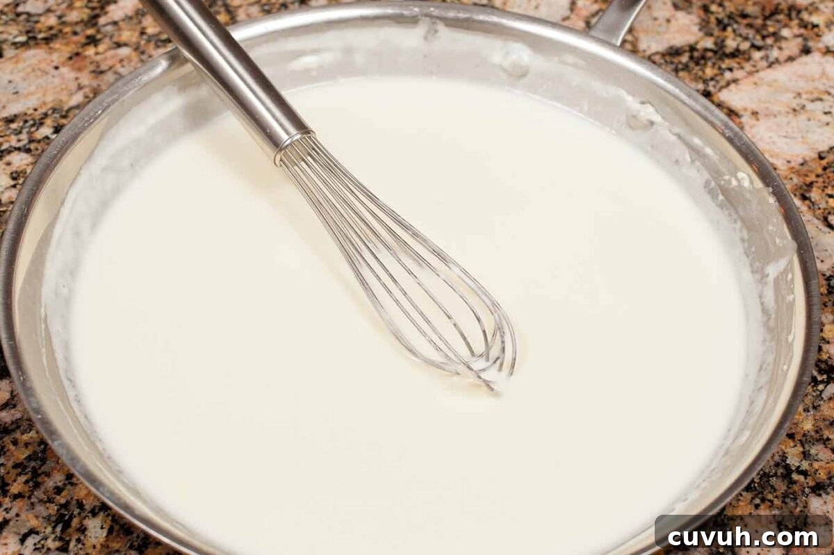 Smooth béchamel sauce thickened and ready for cheese in homemade macaroni and cheese.