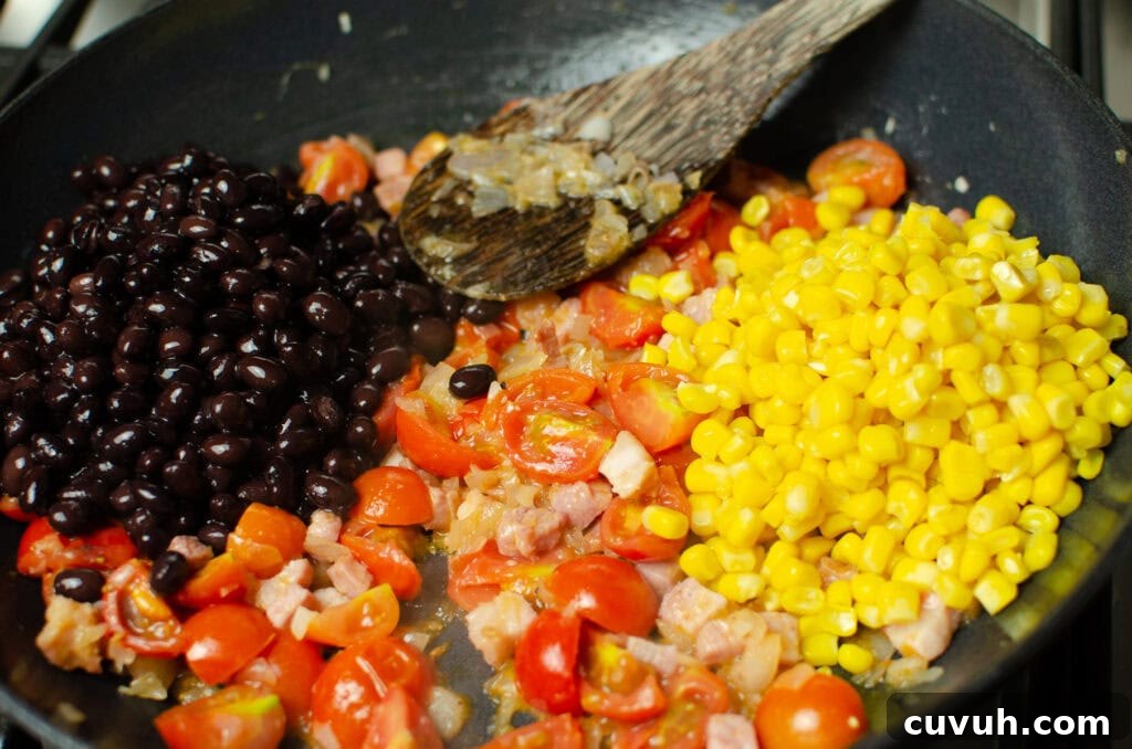Brunch Nachos: Loaded Breakfast Nachos with Eggs & Avocado 4 Black beans and sweetcorn added to the chopped cherry tomatoes,chopped pancetta and chopped onion cooking in a cast iron pan