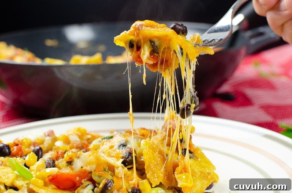 Brunch Nachos: Loaded Breakfast Nachos with Eggs & Avocado 12 Breakfast Brunch Nacho's with gooey melted cheese on a silver fork being served on a white plate