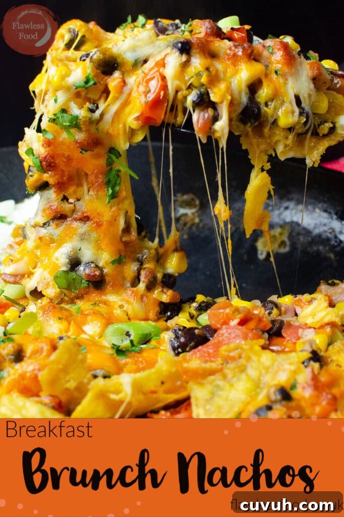Brunch Nachos: Loaded Breakfast Nachos with Eggs & Avocado 13 Pin image of our Breakfast Brunch Nachos in a cast iron pan being picked up with a spatula with melted cheese dripping down
