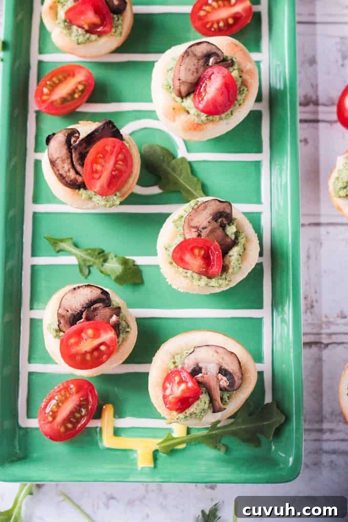 Vegan Pizza Bites - easy pizza dough topped with dairy free pesto, mushrooms and cherry tomatoes. Big bold flavors in a little bite - perfect for your next party or get together! Especially great for game day! Overhead view Vegan Pizza Bites on a green tray.