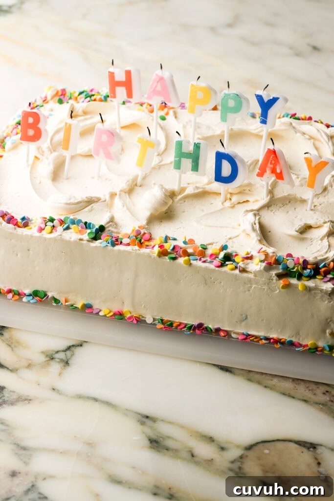 Party-Size Vanilla Birthday Sheet Cake Recipe 26 cake fully frosted and decorated with 'happy birthday' rainbow candles and confetti sprinkles