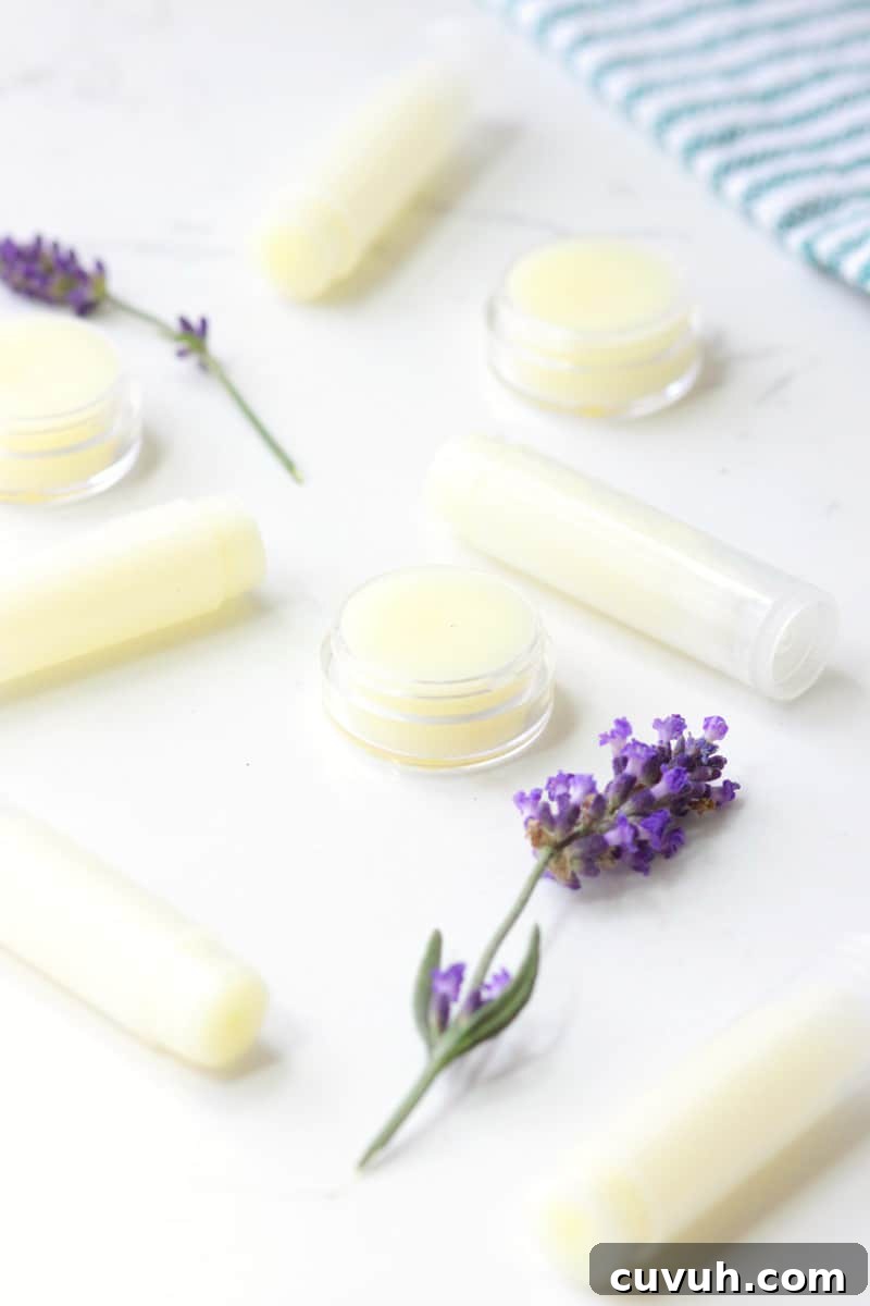a variety of beeswax lip balms laying on a white table surrounded by lavender flowers