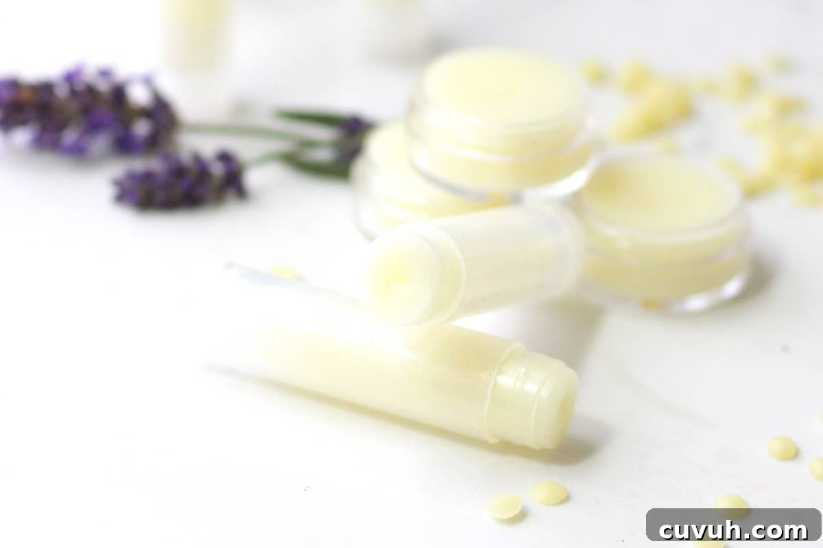a variety of beeswax lip balms laying on a white table surrounded by lavender flowers