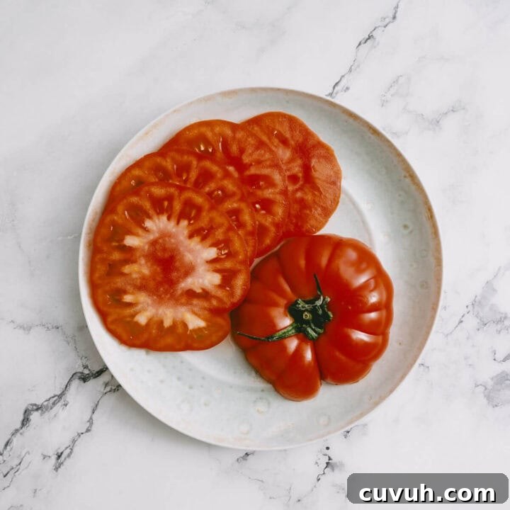 Tomato and Grilled Halloumi Salad with Basil Vinaigrette 5 Sliced heirloom tomatoes on a plate, ready for making halloumi salad.