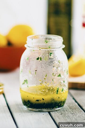 Greek salad dressing made with olive oil, lemon juice and herbs in a small glass jar.