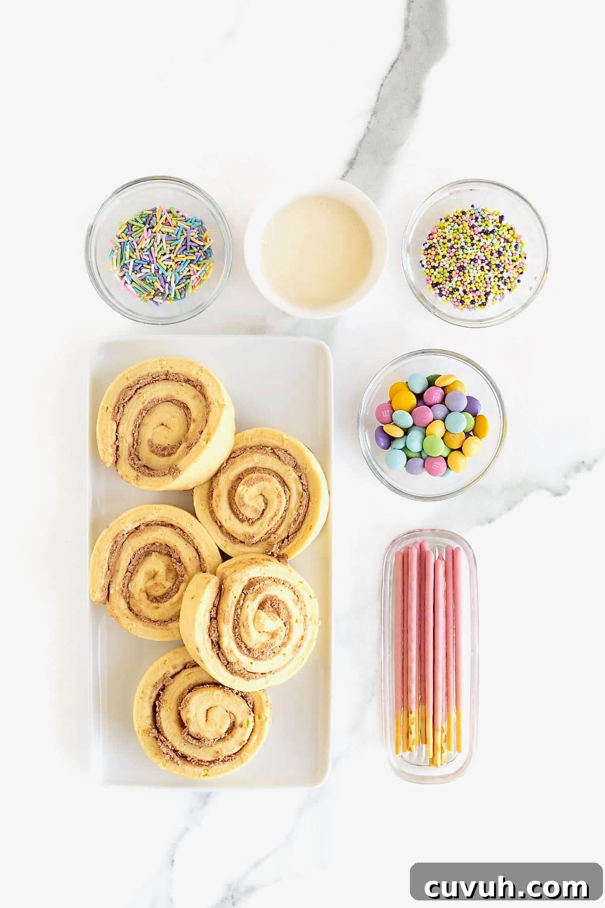 Ingredients to make butterfly shaped cinnamon rolls in small dishes on a white marble counter.