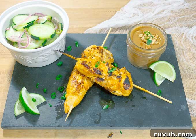 Thai Chicken Satay Skewers on blackslate with cucumbers and peanut sauce