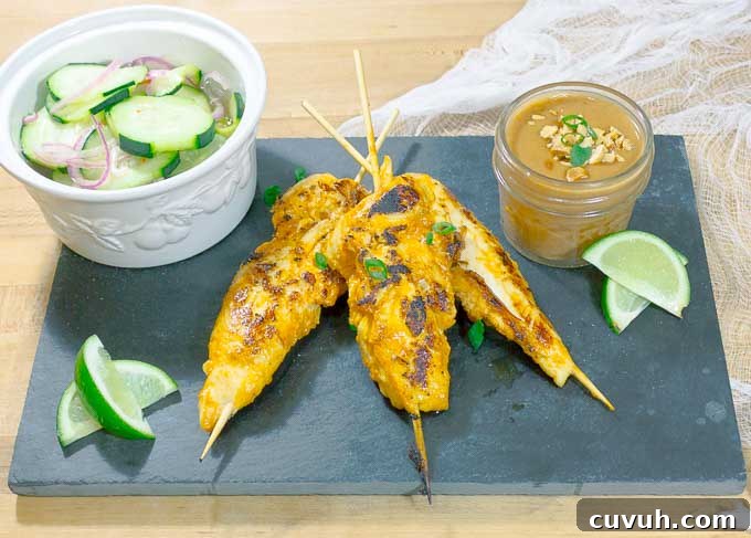 Thai Chicken Satay Skewers on blackslate with cucumbers and peanut sauce