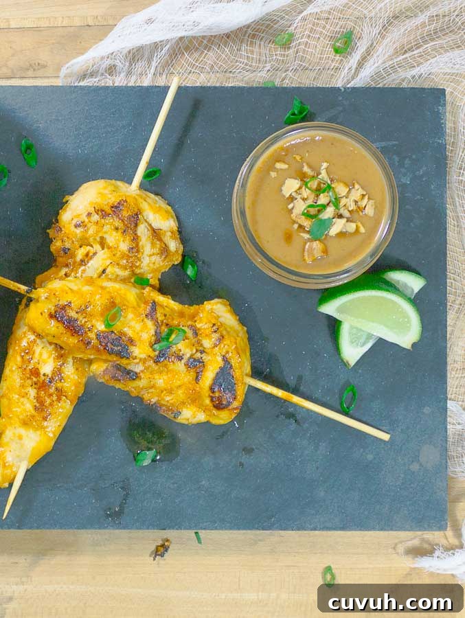 Thai Chicken Satay Skewers on blackslate with cucumbers and peanut sauce
