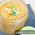 Thai Peanut Sauce Recipe in glad jar with peanut and green onion garnish