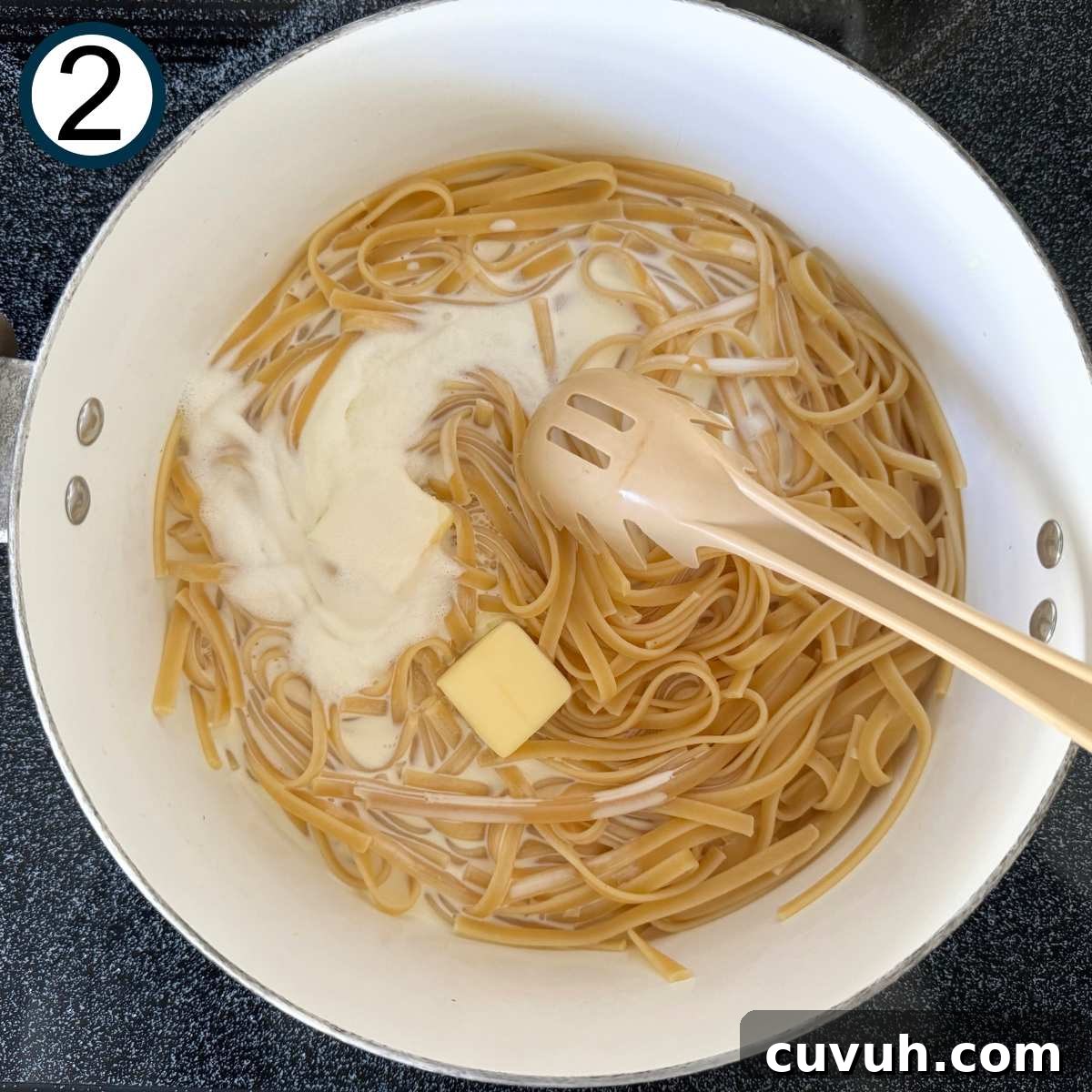 Cooked fettuccine noodles, butter, and heaving cream in a pot.