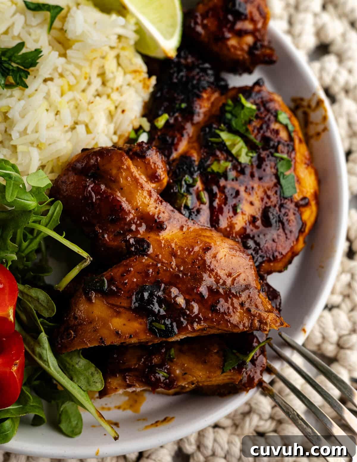 Honey Chipotle Glazed Chicken Thighs Recipe 2 honey chipotle chicken thighs on a plate with rice and salad.