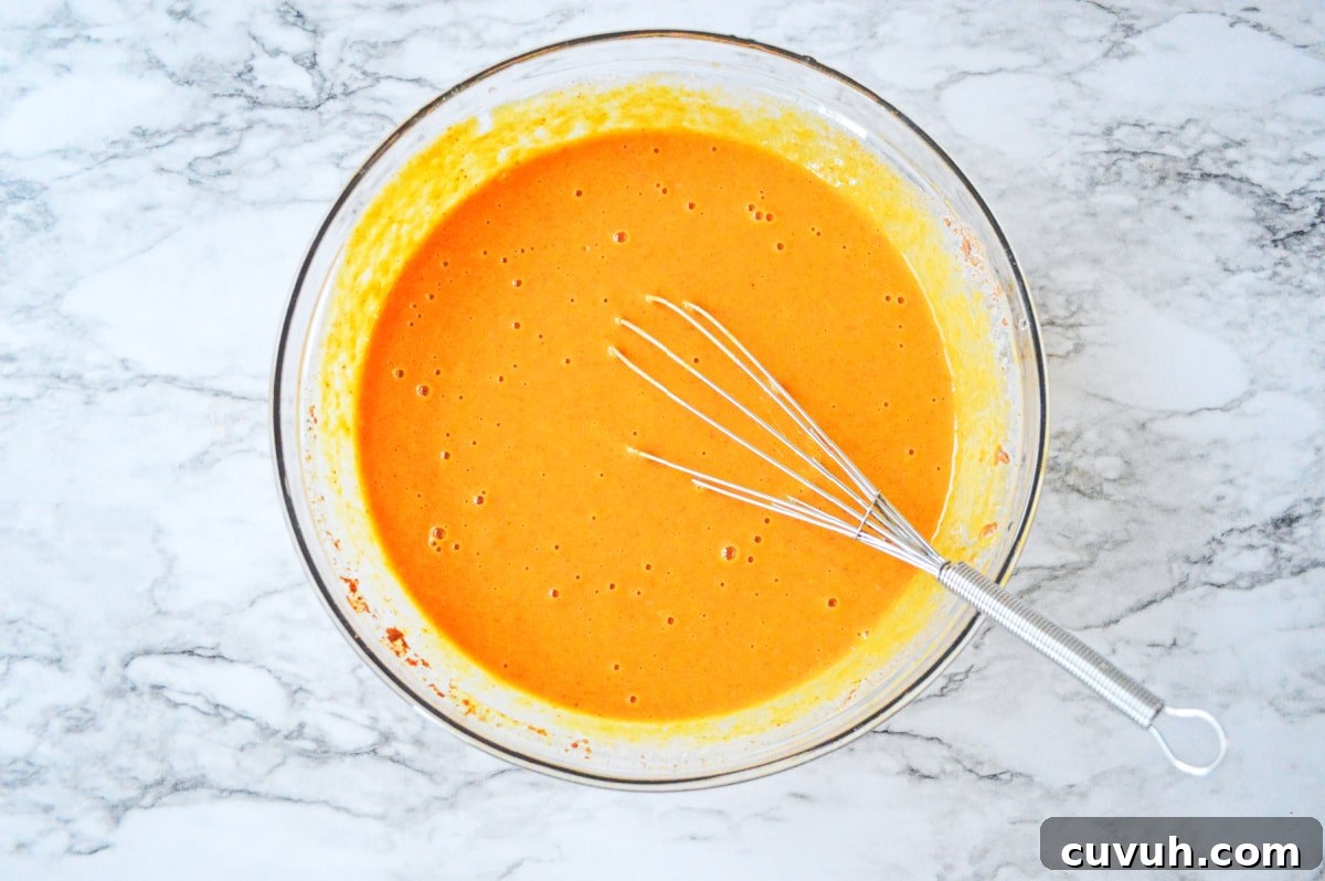 pumpkin cake batter in a glass bowl with whisk