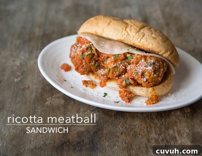 Ricotta-Stuffed Meatball Sandwich with Tomato Sauce 2 ricotta meatball sandwich with provolone cheese on white plate.