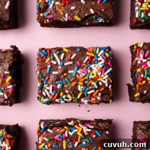 Close up of rainbow sprinkles brownies on a pink background.