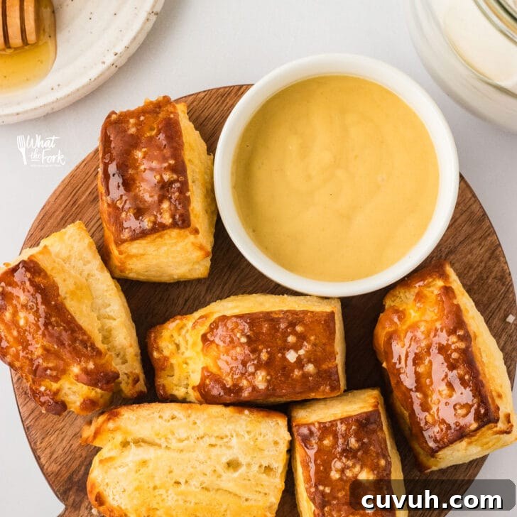 quick, Buttery Pretzel Biscuits made with Gluten Free Flour on a round wood serving board with a small white bowl filled with honey mustard