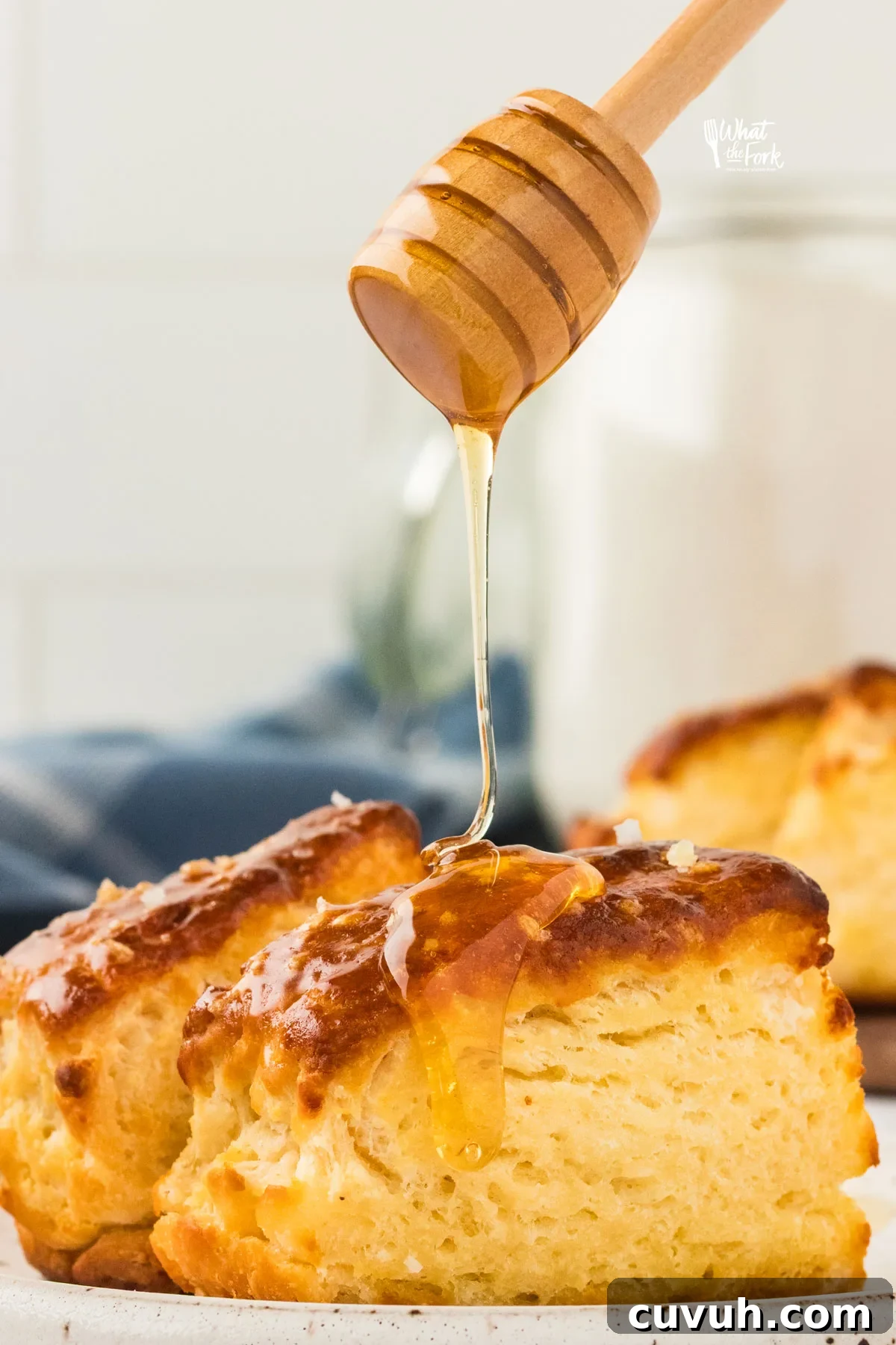 a honey ladle drizzling honey on top of a gluten free pretzel biscuit