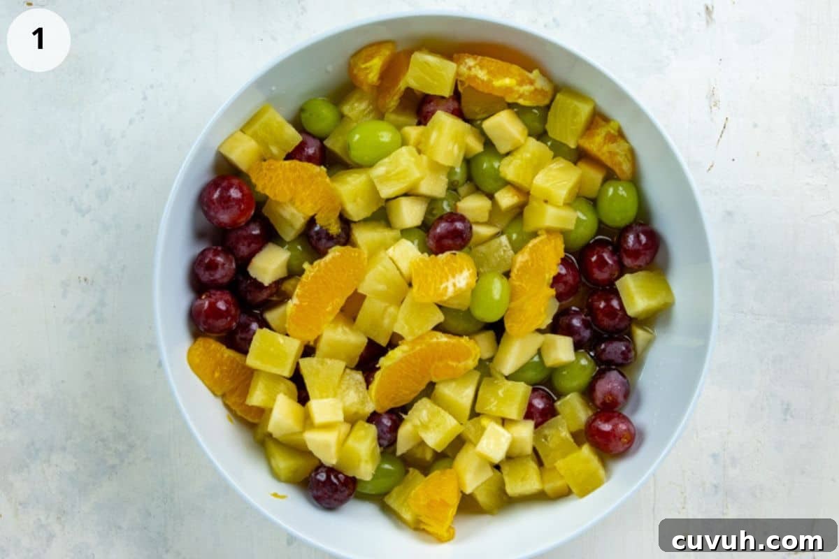 Diced apple, grapes, pineapple chunks, and orange segments in a bowl.