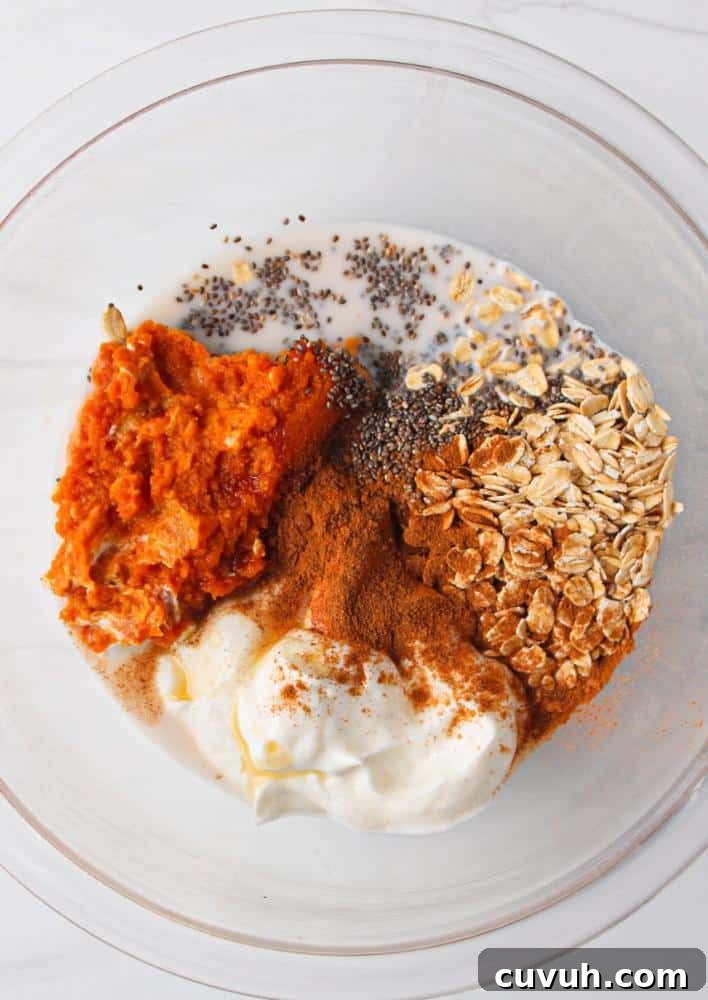 Pumpkin Protein Overnight Oats Recipe for Morning Energy 4 A clear bowl full of pumpkin puree, greek yogurt, vanilla, chia seeds, spices, rolled oats, and maple syrup.