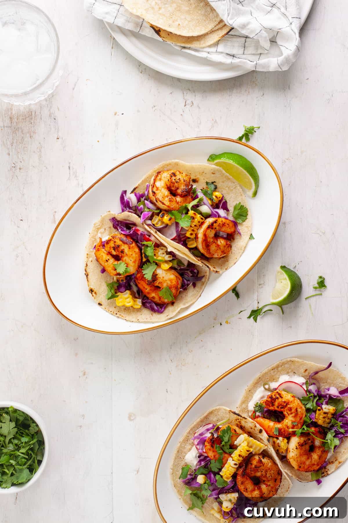 A serving of chili lime shrimp tacos on a small plate with another serving to the side.