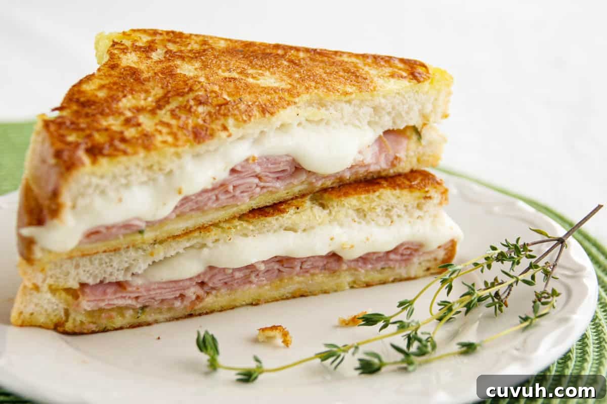 Italian Style Monte Cristo cut in half and stacked with fresh thyme on a plate.