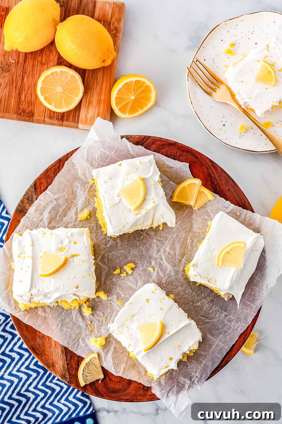 Moist Lemon Poke Cake with Zesty Citrus Glaze 6 Four slices of Lemon Poke Cake on a wooden serving plate.
