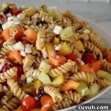 Whole Wheat Greek Pasta Salad with Feta & Olives 7 Whole Wheat Greek Pasta Salad with feta, tomatoes, cucumbers, and bell pepper in an white bowl.