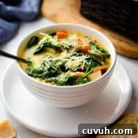 The Instant Pot Zuppa Toscana is in a bowl on a plate with a bread basket in the background