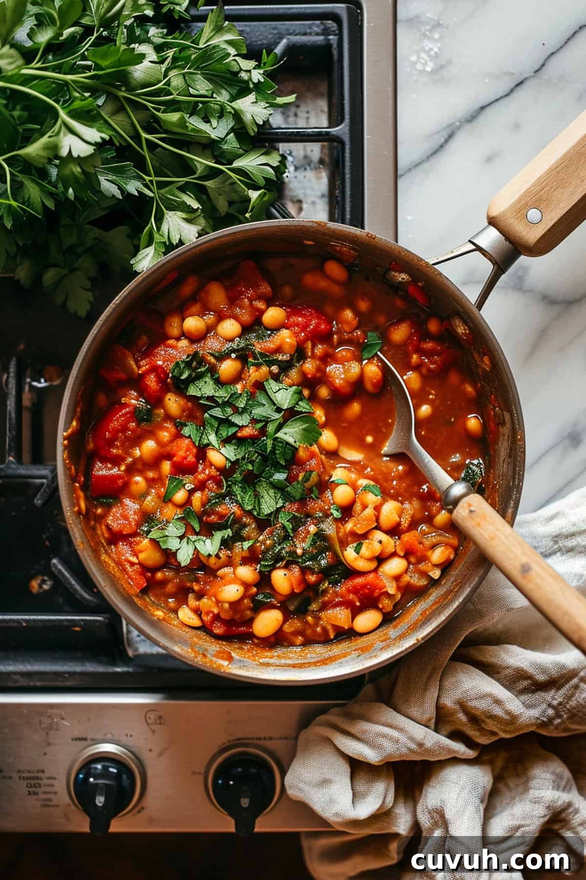 Smoky Moroccan bean stew with cilantro and tomatoes, cooking on the stove.