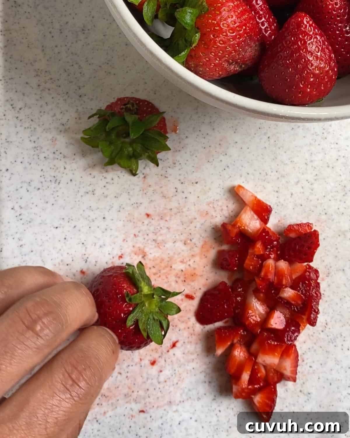 process of cutting strawberries on a white surface