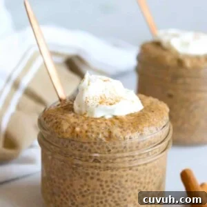 Two glass jars filled with pumpkin chia seed pudding topped with yogurt and cinnamon