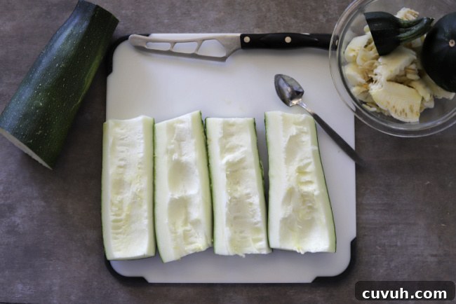 zuccchini, quartered on cutting board with spoon and bowl that contains seeds just scooped out