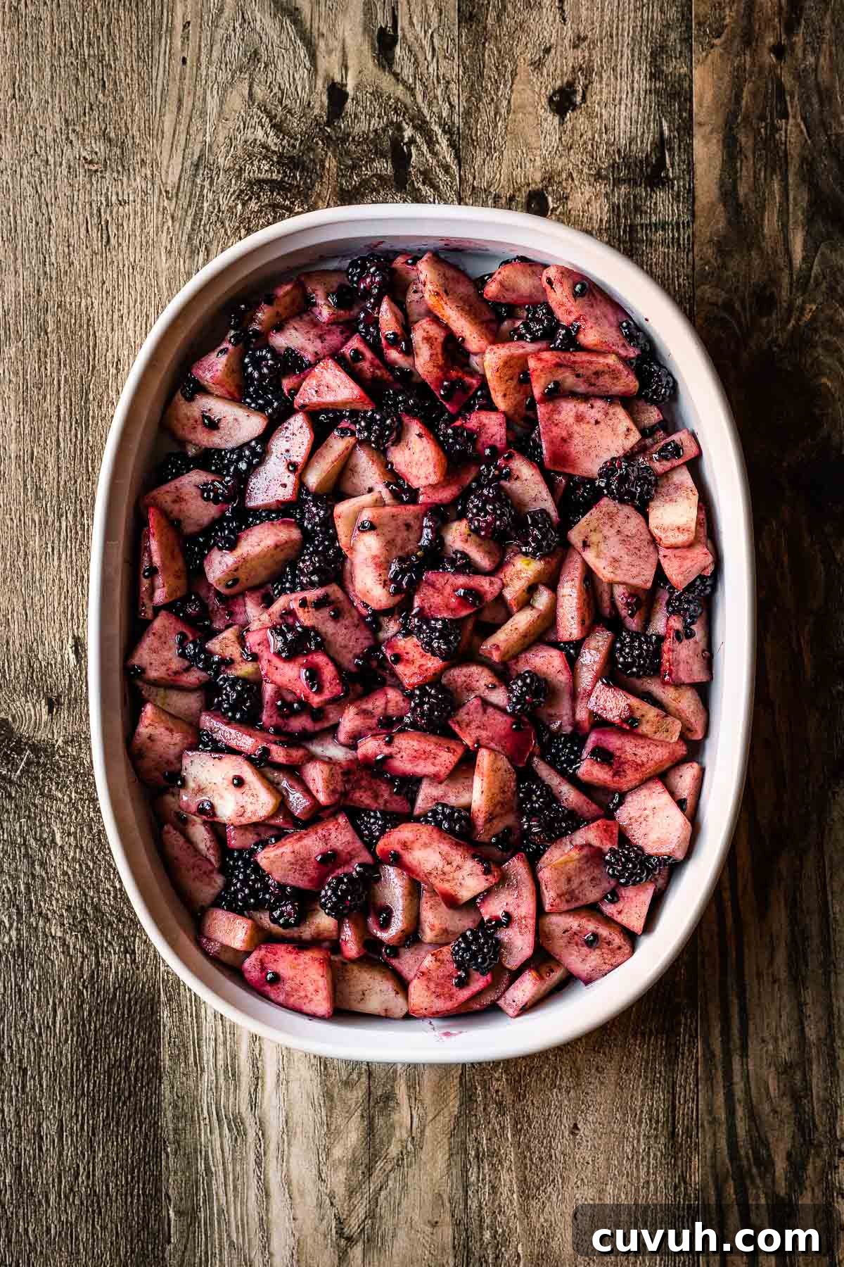 Apple and Blackberry Crumble Recipe for Perfect Autumn Dessert 6 A baking dish filled with uncooked peeled, chopped apples and blackberries.