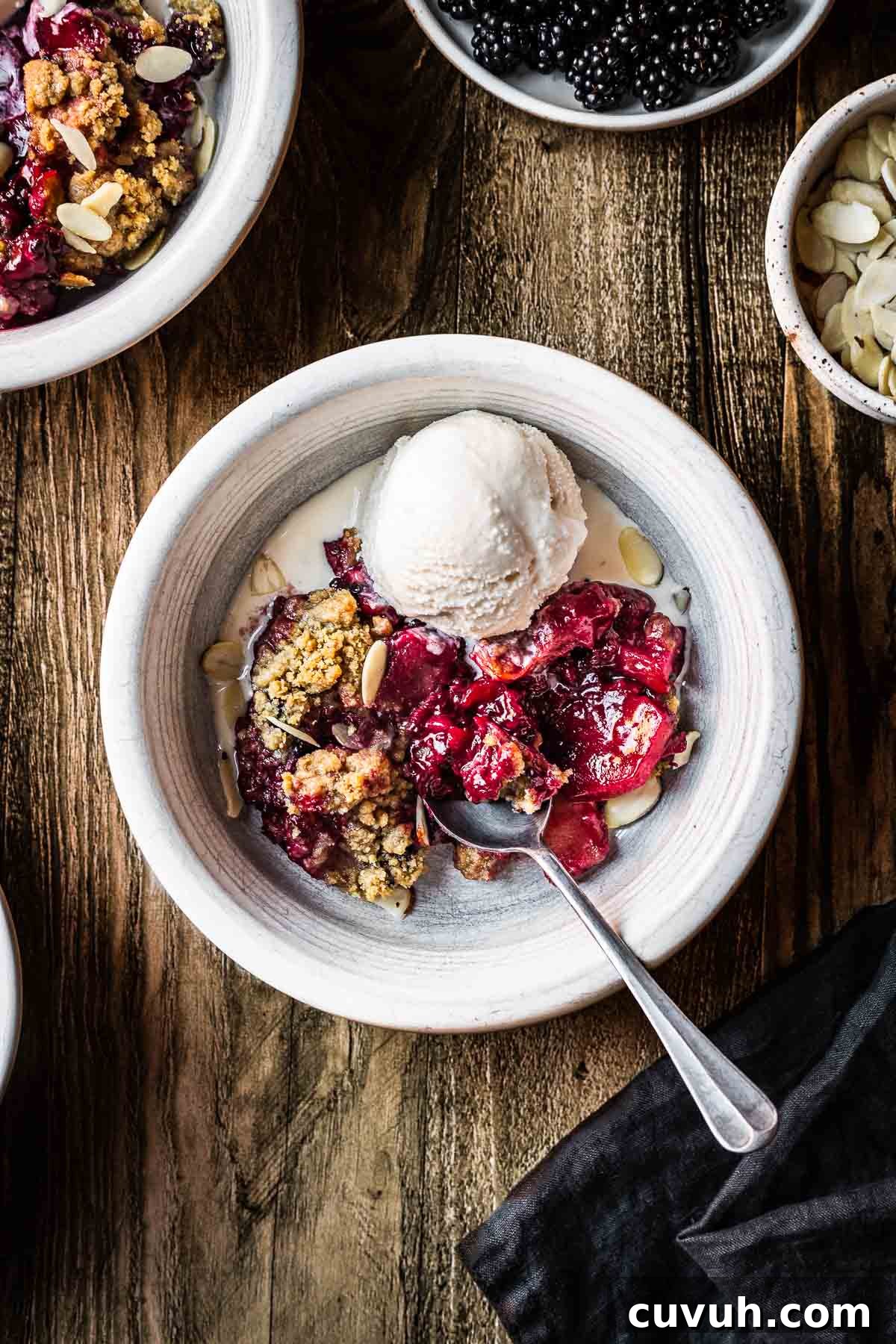 Apple and Blackberry Crumble Recipe for Perfect Autumn Dessert 8 A serving of apple blackberry in a white bowl with a scoop of ice cream.