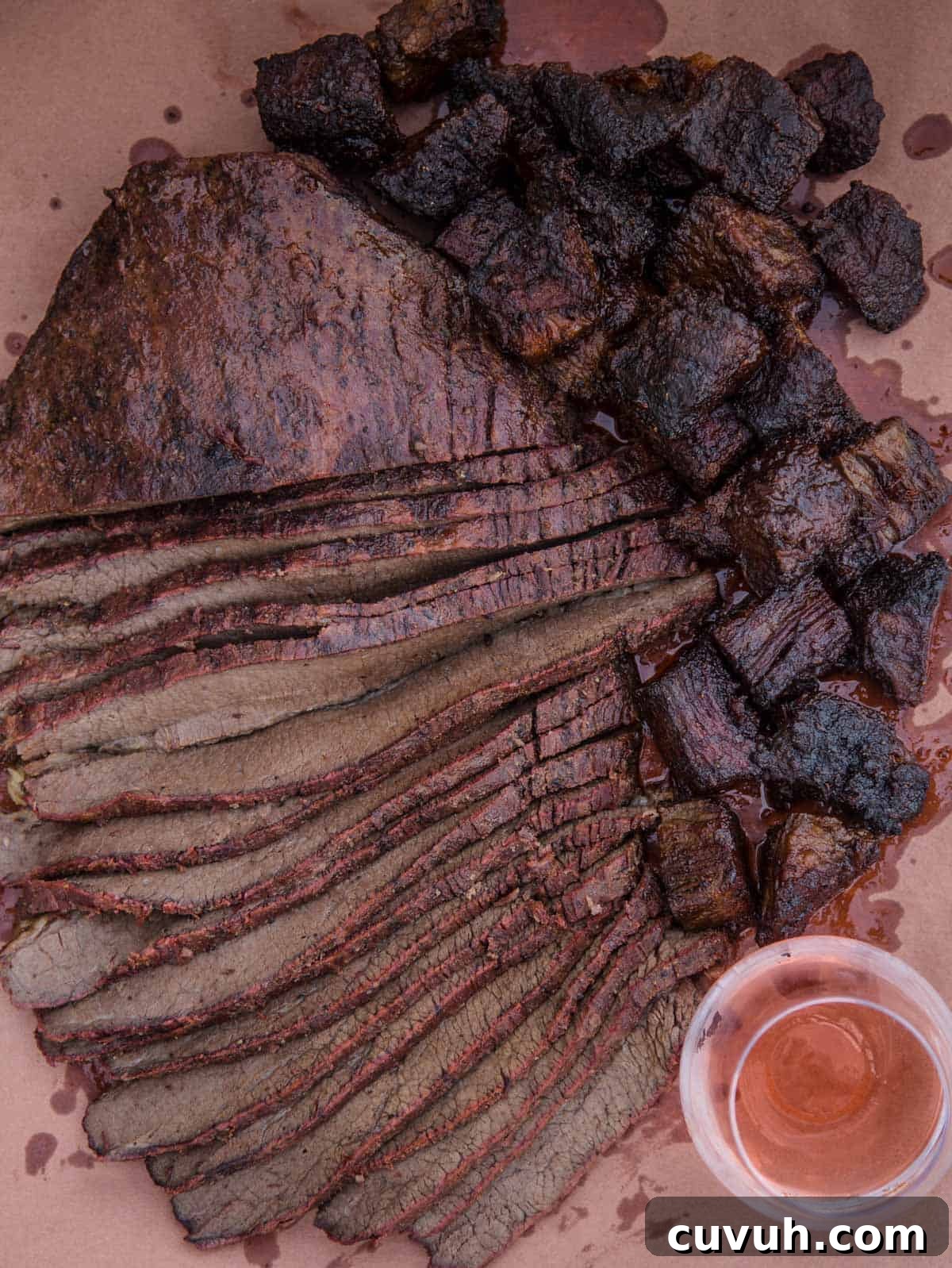 Slices of brisket flat and cubes of BBQ Burnt Ends on a serving dish with a glass of wine
