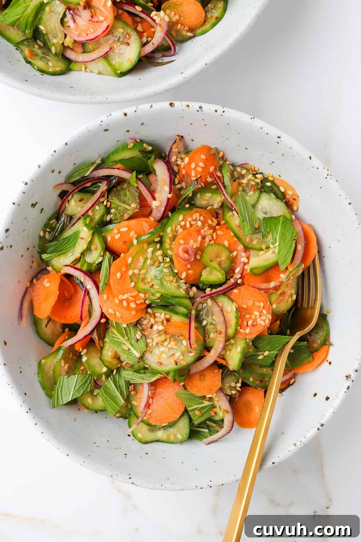 Sesame Carrot and Cucumber Salad with Tangy Dressing 7 Carrot cucumber salad in bowls with fork.