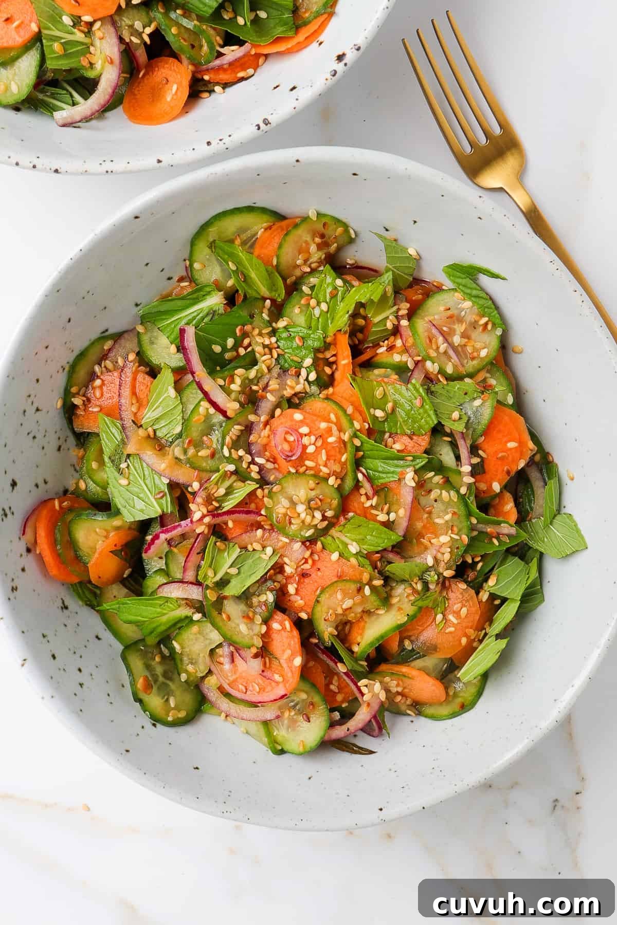 Sesame Carrot and Cucumber Salad with Tangy Dressing 8 Carrot cucumber salad in bowls with fork on the side.