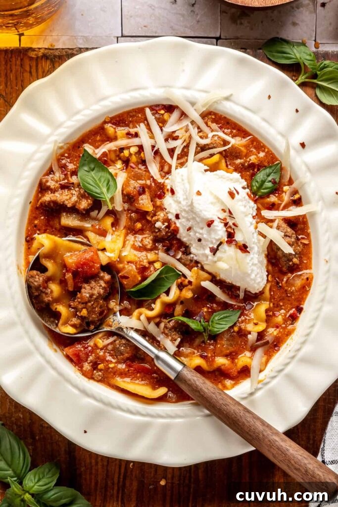 High-protein lasagna soup in a bowl topped with dairy-free ricotta, basil, and chili flakes