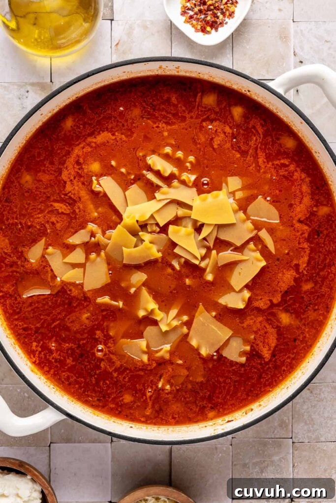 One-pot lasagna soup simmering with ground beef, marinara, and gluten-free lasagna noodles.