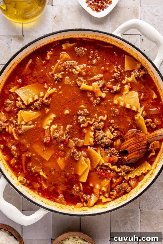 One-pot lasagna soup simmering with ground beef, marinara, and gluten-free lasagna noodles.