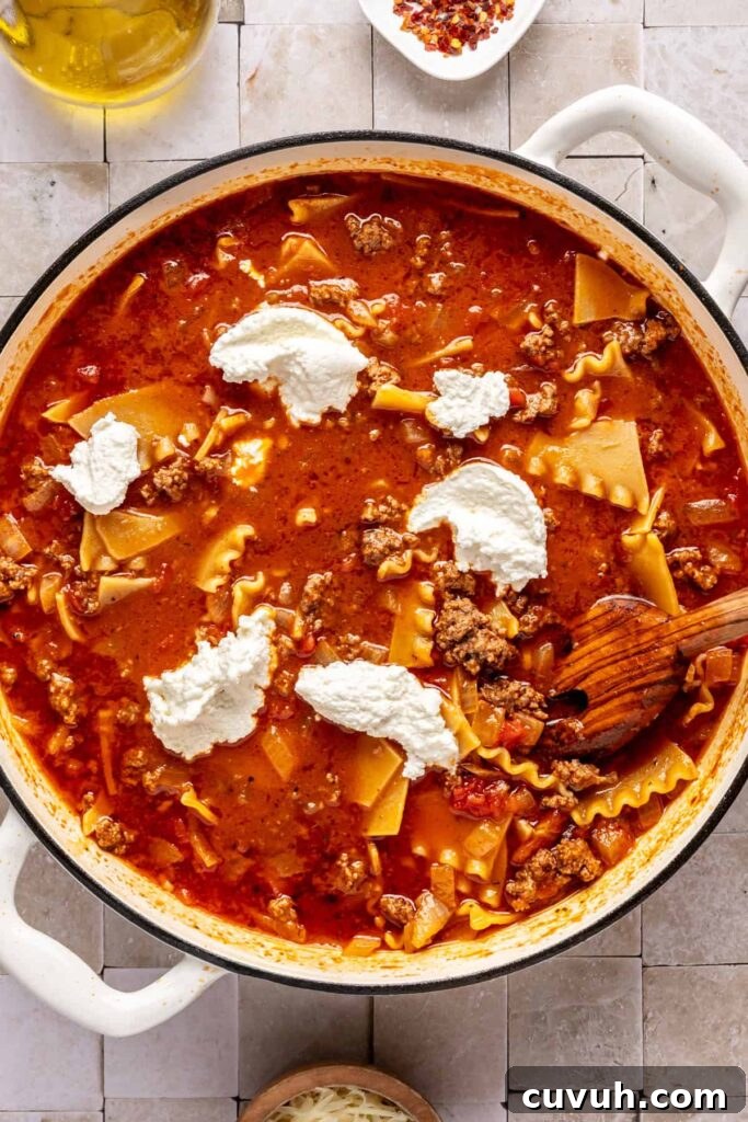 Mixing a one-pot lasagna soup with dairy-free ricotta, ground beef, marinara, and gluten-free lasagna noodles.