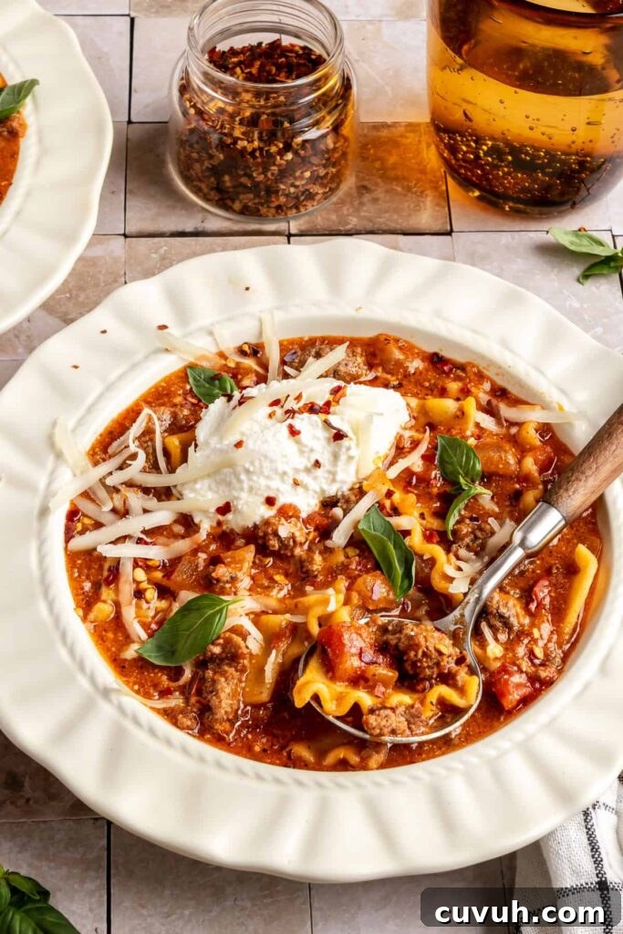 High-protein lasagna soup in a bowl topped with dairy-free ricotta, basil, and chili flakes