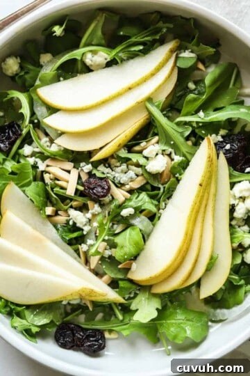overhead view of rocket and pear salad in white bowl