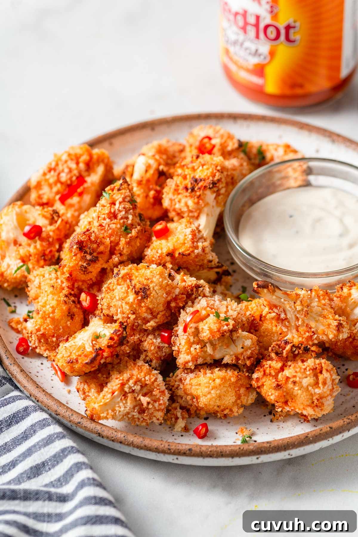 Crispy Air Fryer Buffalo Cauliflower Recipe 2 air fryer buffalo cauliflower bites on a plate with a creamy dip.