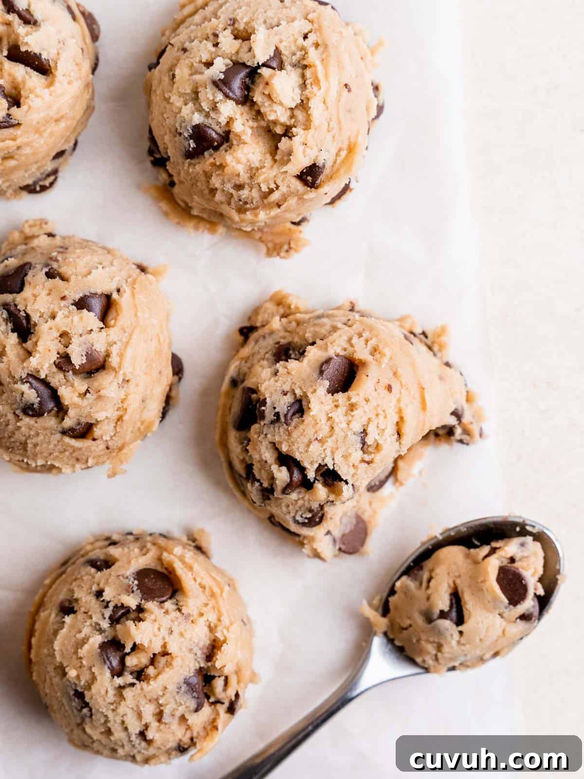 Top view of cookie dough scoops on a sheet of parchment paper.