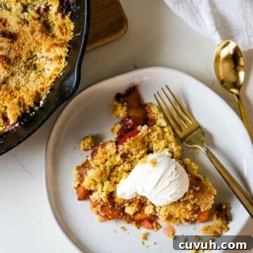 peach cobbler with vanilla ice cream on white plate.
