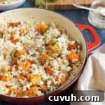 Butternut squash and bacon risotto in a red pan garnished with parsley.