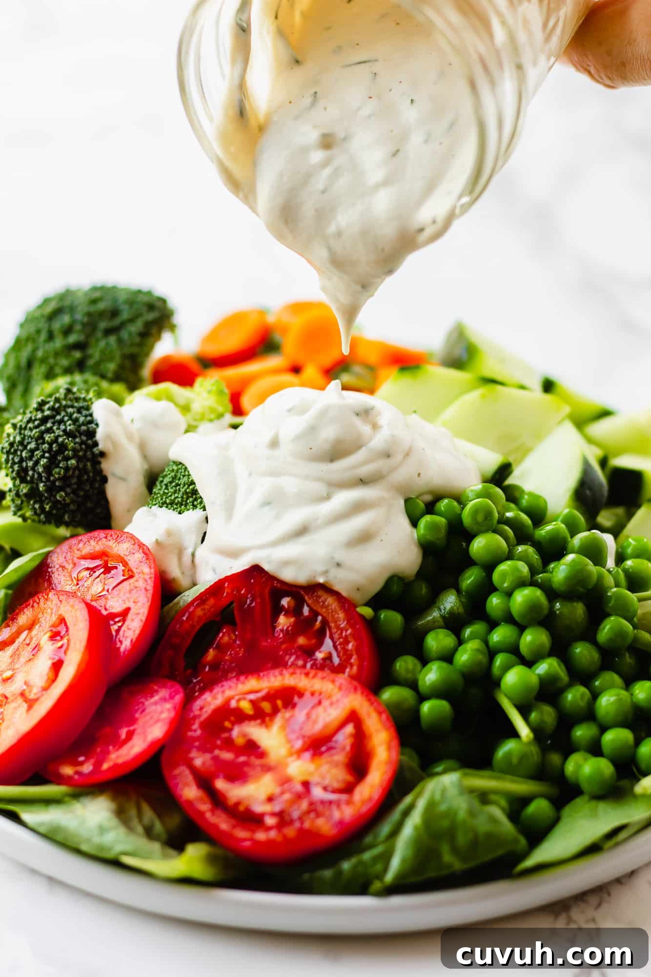 Creamy Vegan Ranch Dressing Recipe for Salads & Dips 2 pouring vegan ranch dressing over a large green salad.
