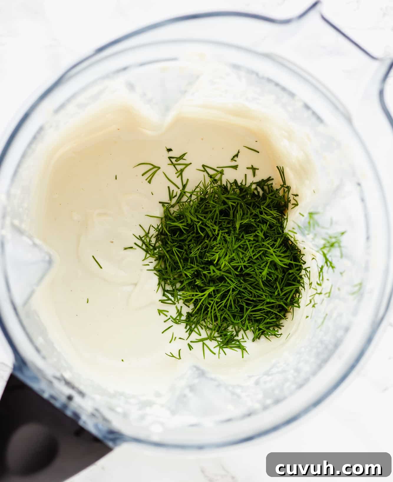 Creamy Vegan Ranch Dressing Recipe for Salads & Dips 4 fresh dill on top of a creamy white sauce in a blender.